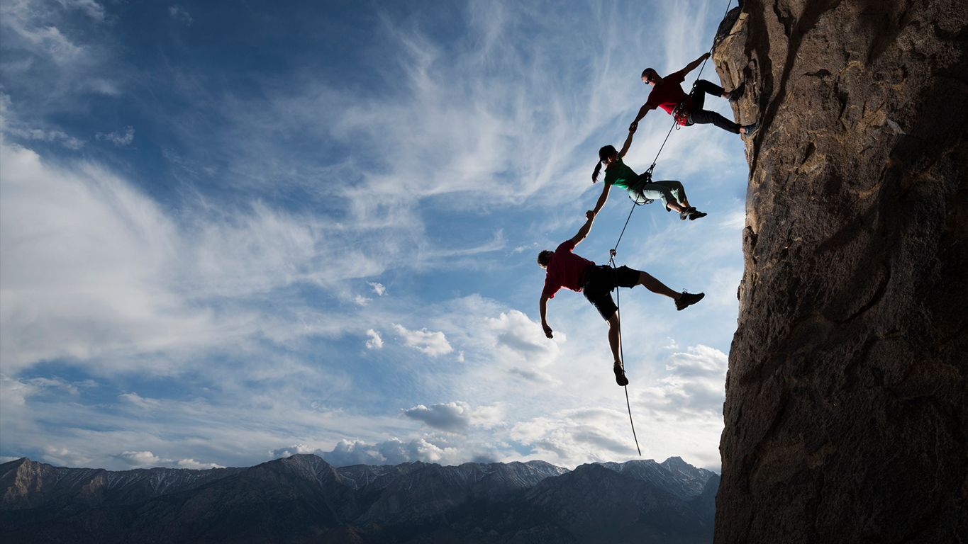 Three climbers supporting each other on a rock face, representing trust, assurance, and human oversight in high-stakes environments like responsible AI